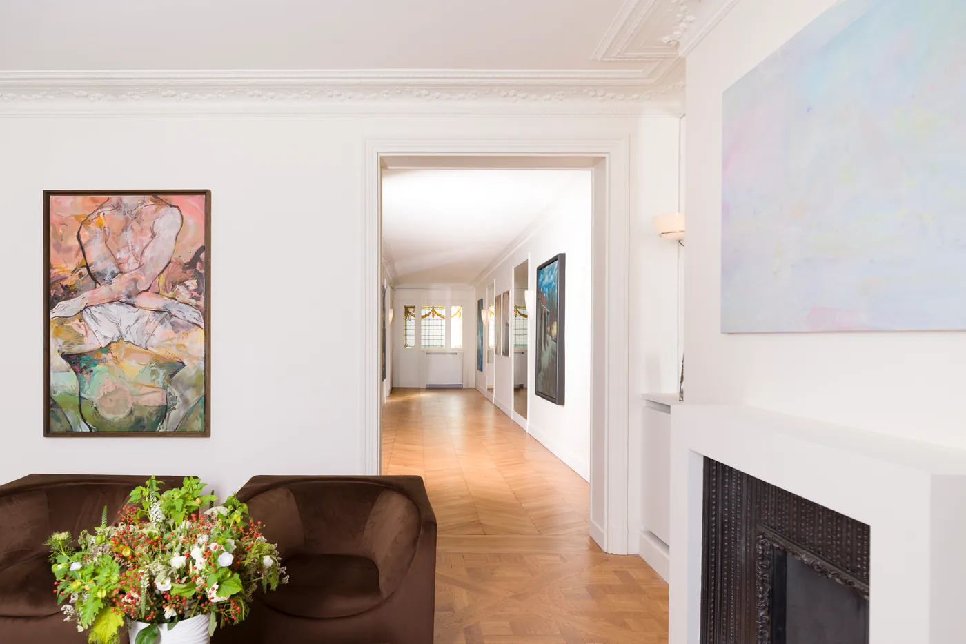 Paintings on the walls of an apartment, with a view down a long corridor